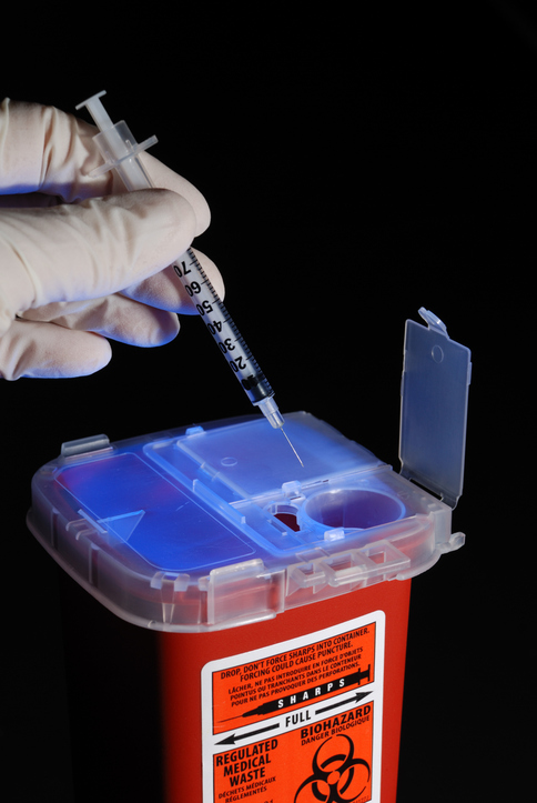 Inserting a needle into a sharps container