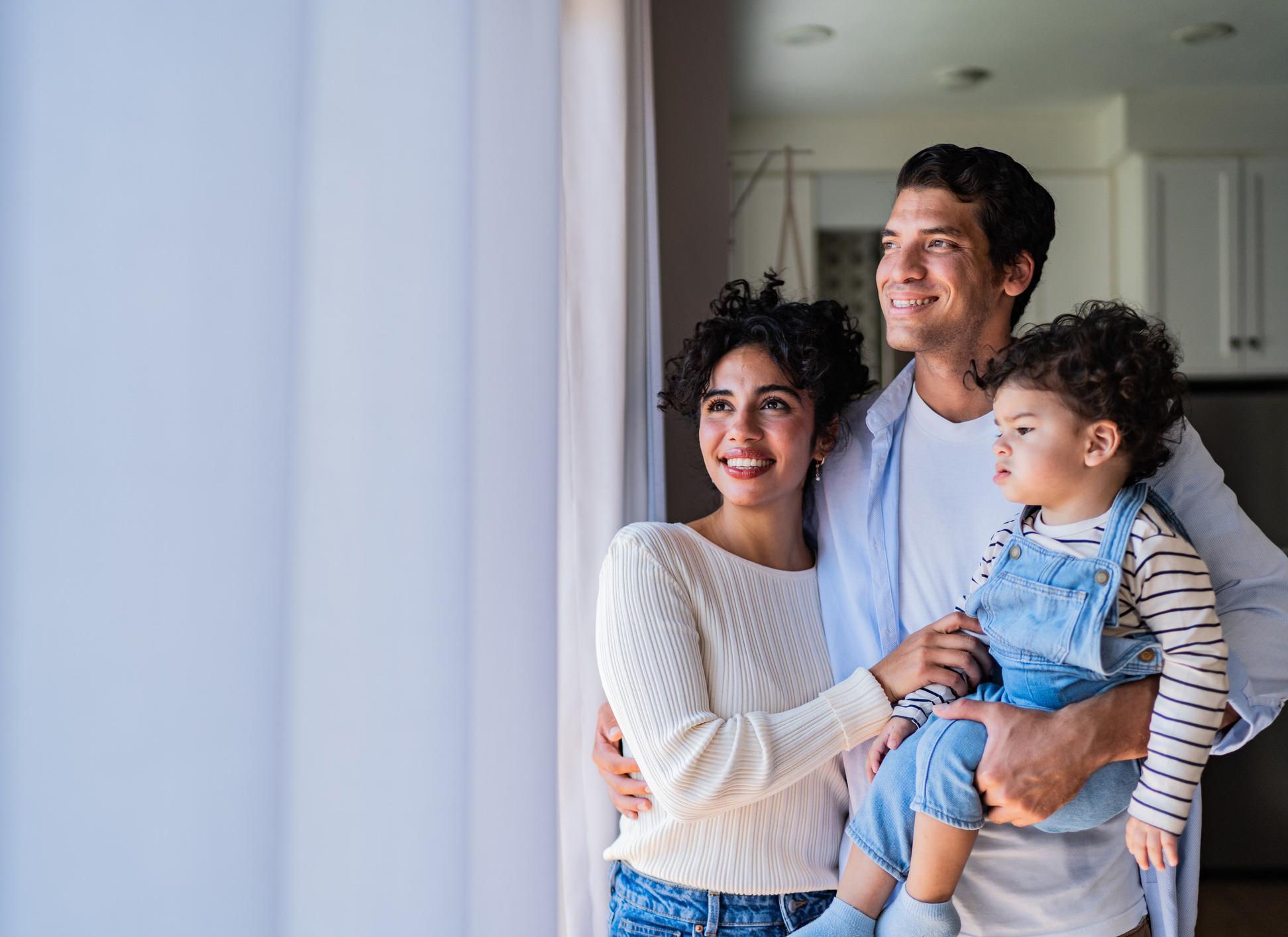 Family with baby boy talking and looking through window at home